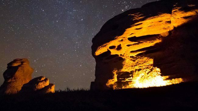 light of camp fire on rock face